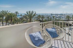 2 wiklinowe krzesła z niebieskimi poduszkami na balkonie w obiekcie YupiHome Mariners Apartment w Alcudii