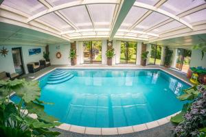 an indoor swimming pool with a glass ceiling at Badgers Den - Covehurst Bay Holiday Cottage in Hastings