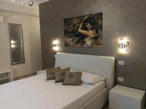 a bedroom with a white bed and a painting on the wall at B&B Il Mare degli Dei in Letojanni