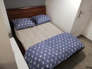 a small bed with a blue comforter and pillows at Maison Duplex & Appartement sur cour in La Ferté-Gaucher