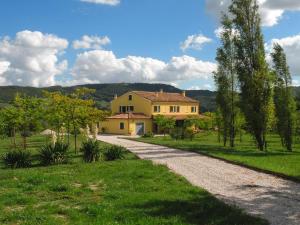 a house in a field with a gravel road at Agriturismo Calamello in Pergola