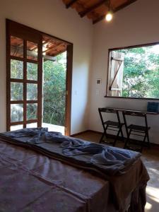 a large bed in a room with two windows at Chalé da Mangueira in Vale do Capao