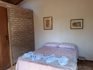 a bedroom with a bed with a blue bow on it at Chalé da Mangueira in Vale do Capao