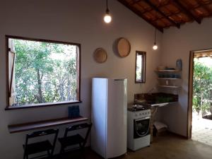 a kitchen with a refrigerator and a stove and a window at Chalé da Mangueira in Vale do Capao