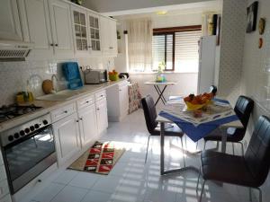 a kitchen with white cabinets and a table with a bowl of fruit on it at Rota das praias in Figueira da Foz