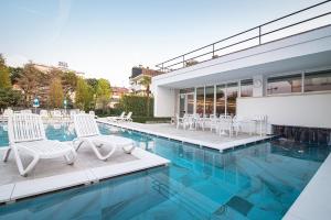 una piscina con sedie bianche e una casa di Hotel Terme Vena D'Oro ad Abano Terme