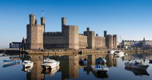 a castle with boats in the water in front of it at High St. Hideout in Caernarfon