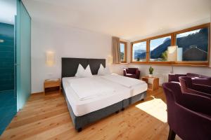 een slaapkamer met een bed en 2 stoelen en een raam bij B&B Villa Angelino in Ortisei