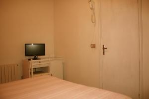 1 dormitorio con 1 cama, TV y puerta en Albergo Villa Dionori, en Chianciano Terme