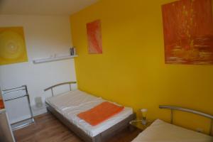 - une chambre avec 2 lits et un mur jaune dans l'établissement Ferienhaus Bambus, mit Blick auf das Hooksieler Tief, à Horumersiel