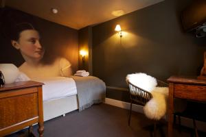 um quarto com uma cama com uma mulher em The Kings Arms em Didmarton