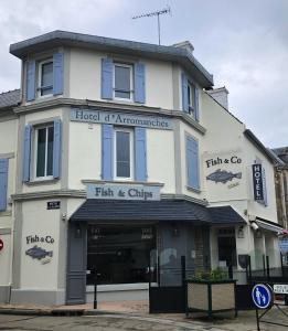 a tall white building with a fish and chips at Hôtel d'Arromanches Pappagall in Arromanches-les-Bains