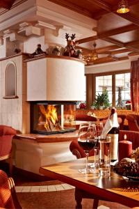 a living room with a fireplace and a table with wine glasses at Hotel Jägerhof in Gerlos