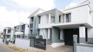 a white house with a black door on a street at Albisville Hilltop Mansion in Ooty