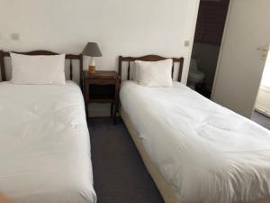 two twin beds in a room with a night stand at Hôtel d'Arromanches Pappagall in Arromanches-les-Bains