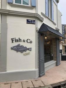 a fish and co sign on the side of a building at Hôtel d'Arromanches Pappagall in Arromanches-les-Bains