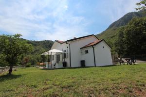 a white house with a picnic table in a field at Bungalow 4 Suns in Virpazar