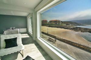 een kamer met een groot raam met uitzicht op het strand bij Apartamento Mirador de Corme in Corme-Puerto