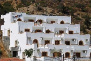 un grand bâtiment blanc au sommet d'une colline dans l'établissement Sunlight Hotel, à Agia Galini