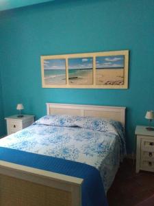 - une chambre avec un mur bleu, un lit et deux fenêtres dans l'établissement Onda Blu Feels Like Home, à San Vito Lo Capo