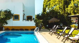 una piscina con sedie e un tavolo accanto a una casa di Casa de Cacela a Vila Nova de Cacela