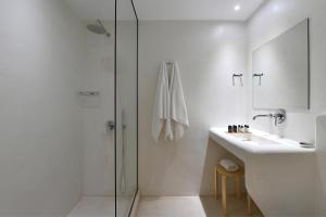 a white bathroom with a sink and a shower at Ammos Luxury Rooms & Home in Naousa