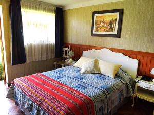 Un dormitorio con una cama con una manta colorida y una ventana. en Hotel Colomba, en Huaraz