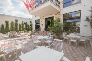 a patio with white tables and chairs outside of a building at Golden Hotel in Pristina