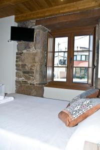 a bed sitting in front of a window next to a wall at PENSION SERRANO in Sarria