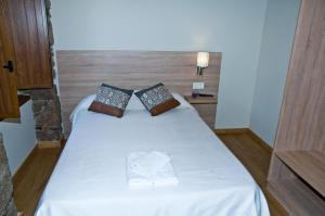 a bedroom with a bed with white sheets and pillows at PENSION SERRANO in Sarria