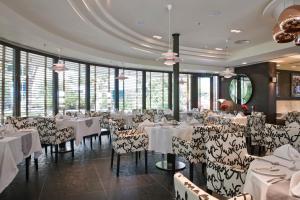 a restaurant with white tables and chairs and windows at Elite Seef Residence And Hotel in Manama