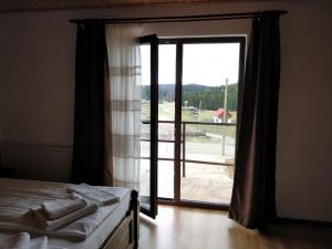 a bedroom with a bed and a sliding glass door at Pensiunea Simiriam Apuseni, Padis in Padis