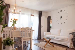 ein Wohnzimmer mit einer weißen Couch und einer Uhr an der Wand in der Unterkunft Apartment JoniFee am Titisee in Titisee-Neustadt