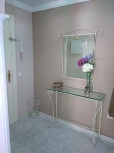 a vase of flowers on a glass table in a bathroom at Fuengirola Puerto Sun&Beach in Fuengirola