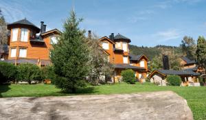 a large wooden house with a christmas tree in front of it at Dormi del Pellin in San Martín de los Andes