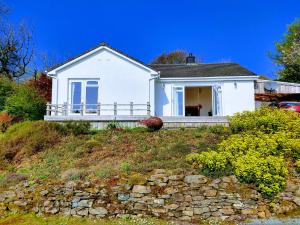 a white house on a hill with a stone wall at Drumgarry in Ardvasar