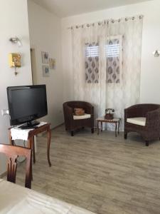 salon z telewizorem z płaskim ekranem i krzesłami w obiekcie Nuovo Appartamento In Centro w Puli