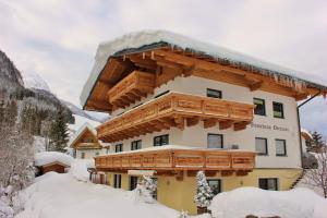 budynek z drewnianym balkonem w śniegu w obiekcie Gästehaus Oberauer w mieście Annaberg im Lammertal