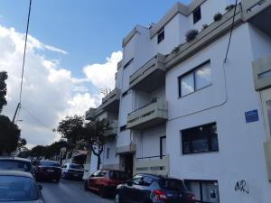 een wit gebouw met auto's op straat bij Nest of Marmel Luxury Studio in Chania