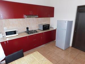 a kitchen with red cabinets and a white refrigerator at Pensiunea Agroturistica Havanna in Zalău