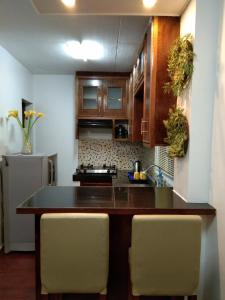 une cuisine avec des placards en bois et un îlot de cuisine avec des chaises dans l'établissement Pensio de Felipe, à Tagaytay