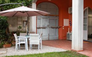 een tafel en stoelen met een parasol op een terras bij La Suite di Bonnes Vacances in Pietrasanta