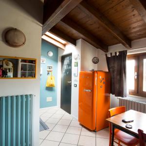 ブレシアにあるMansardine Metropolitaneのキッチン(オレンジ色の冷蔵庫、テーブル付)