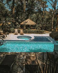 uma piscina com cadeiras e um guarda-sol em Gamboa Eco Refugio Pousada em Iporanga