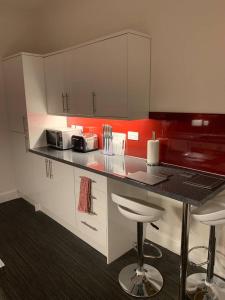 a kitchen with white cabinets and a counter with stools at Apartment 39c in Oban
