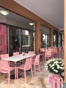 un restaurante con sillas rosas, mesas y ventanas en Hotel Giongo, en Spotorno