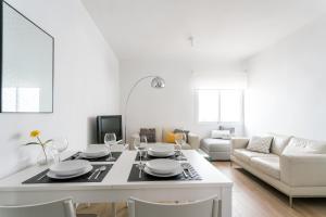 ein weißes Wohnzimmer mit einem Tisch und einem Sofa in der Unterkunft TRIANA 3 Bedrooms & 2 bath Parking Included in Sevilla