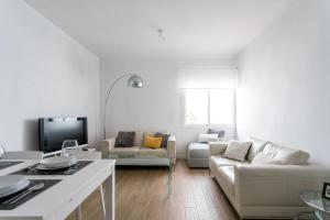 ein weißes Wohnzimmer mit einem Sofa und einem TV in der Unterkunft TRIANA 3 Bedrooms & 2 bath Parking Included in Sevilla