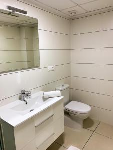 Un baño con inodoro, lavabo y espejo. en Residencial El Pinet Beach, en La Marina