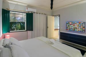 - une chambre avec un grand lit blanc et une télévision à écran plat dans l'établissement Casa Condominio Piccola Paraty, à Parati